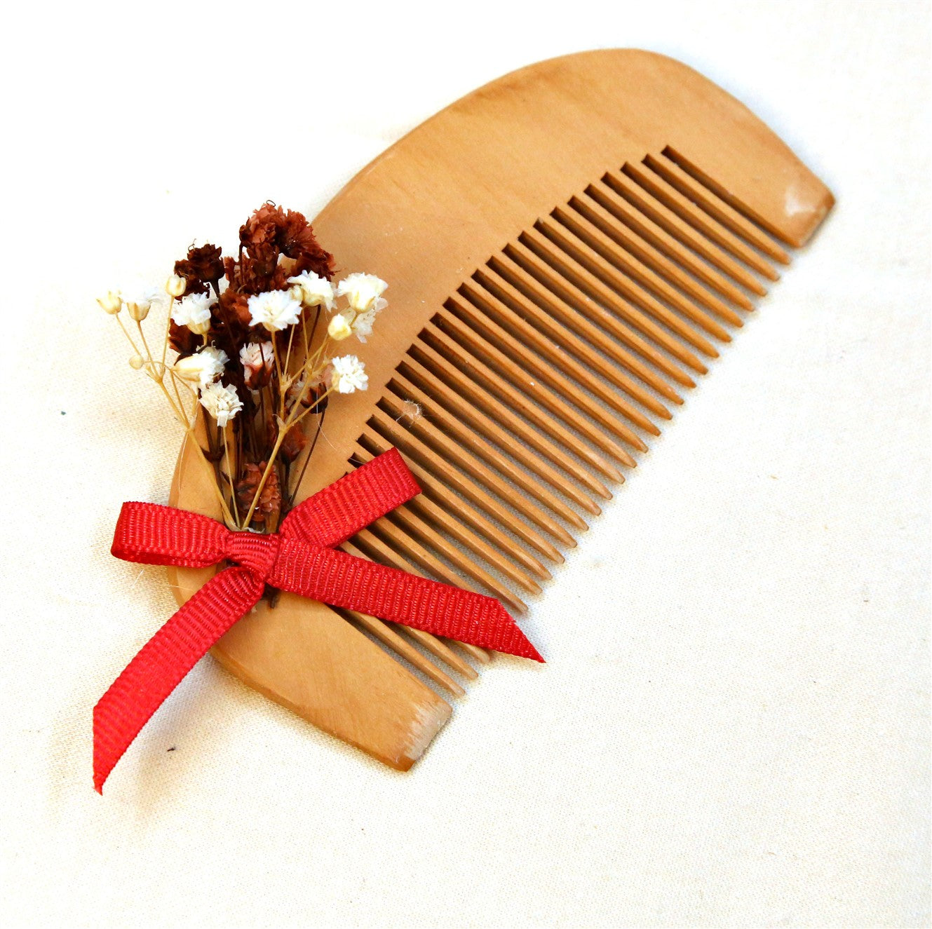 Holzkamm Gastgeschenk mit roter Schleife und Trockenblumen