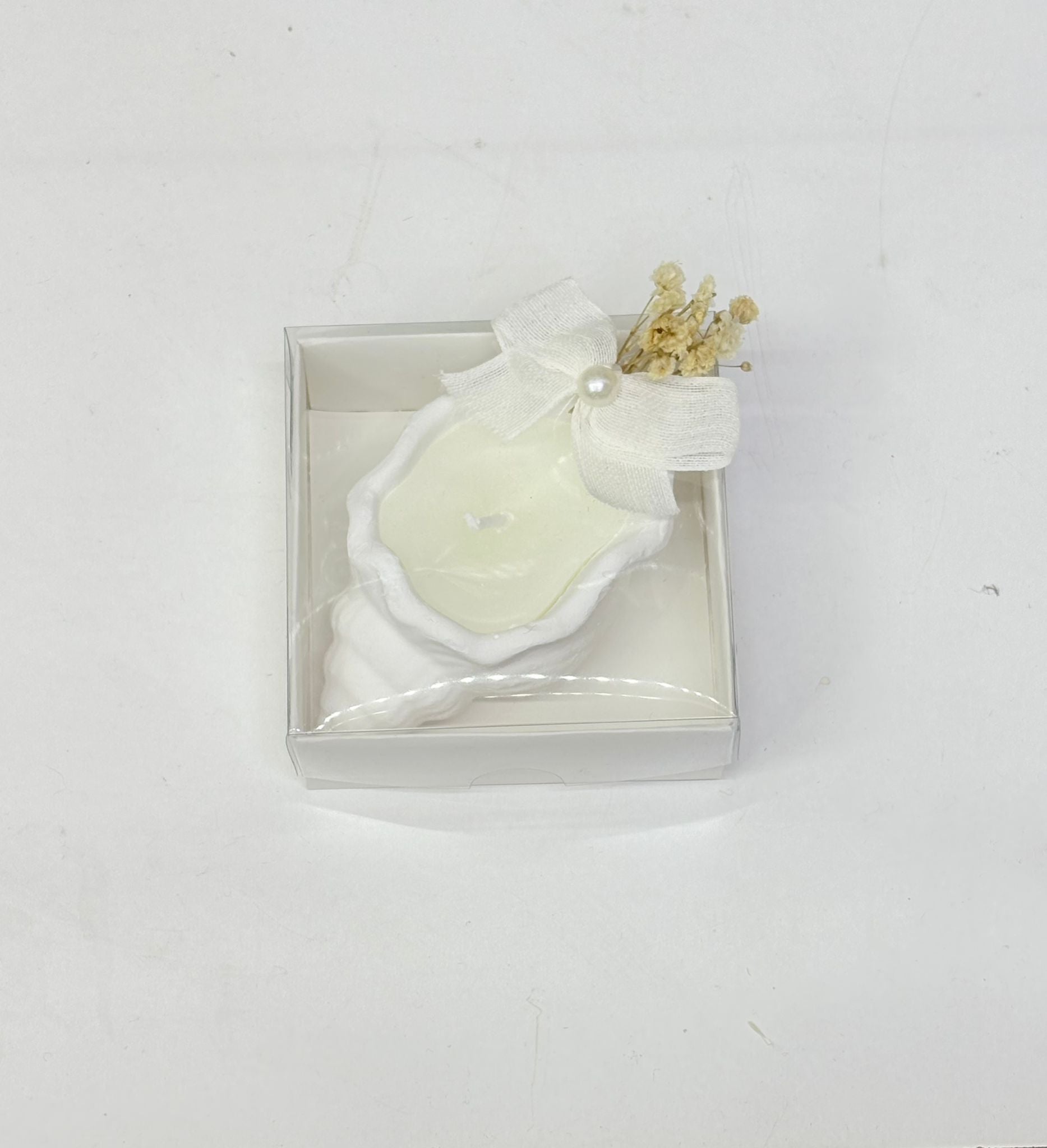 Weiße Muschelkerze in transparenter Box mit Schleife und Trockenblumen