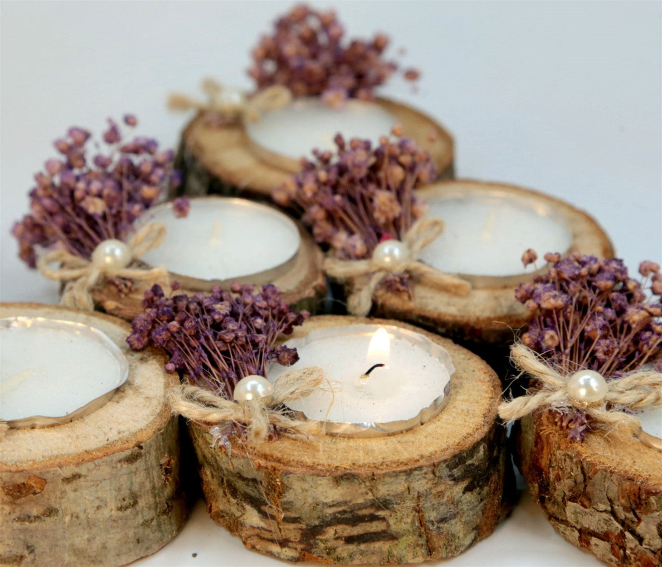 Kleine Kerze in natürlicher Holzscheibe mit lila Trockenblumen und Perle