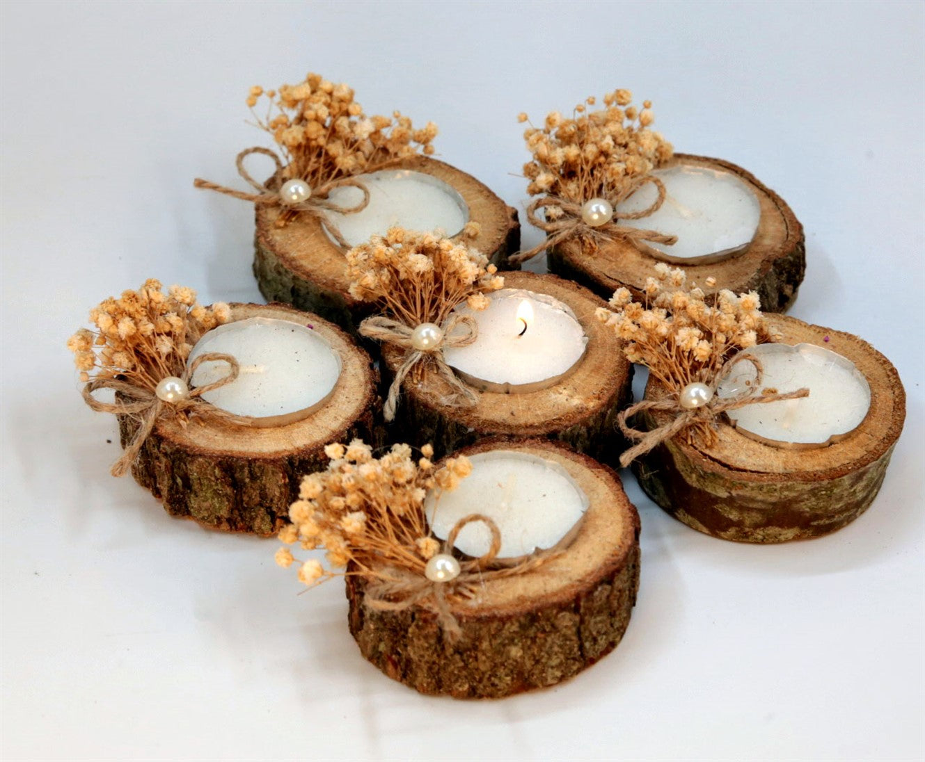 Kleine Kerze in natürlicher Holzscheibe mit Trockenblumen und Perle