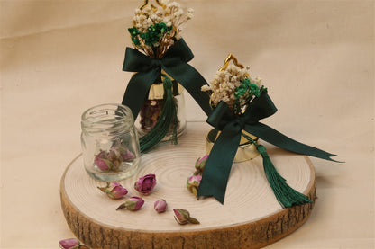 Personalisiertes Glasfläschchen mit getrockneten Rosenknospen, grüner Schleife und Trockenblumen