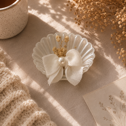 Weiße Kerze in Muschelform mit Schleife und Trockenblumen